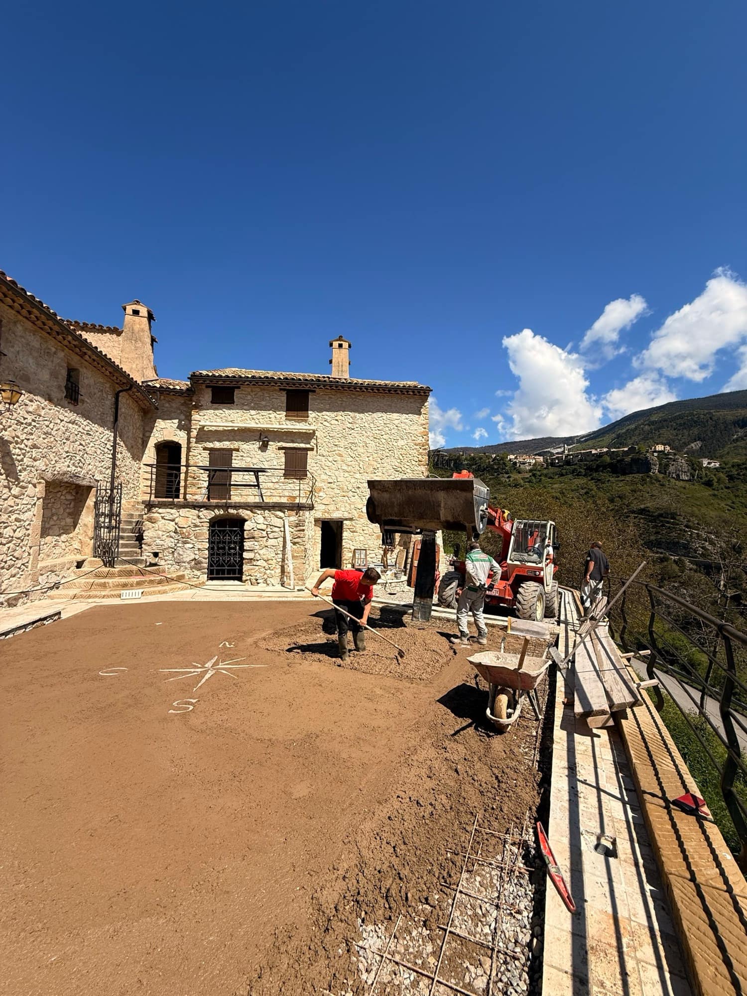 Bastide en pierre restaurée par la SARL MASSE, terrasse en cours de finition, village perché et montagnes en arrière-plan.
