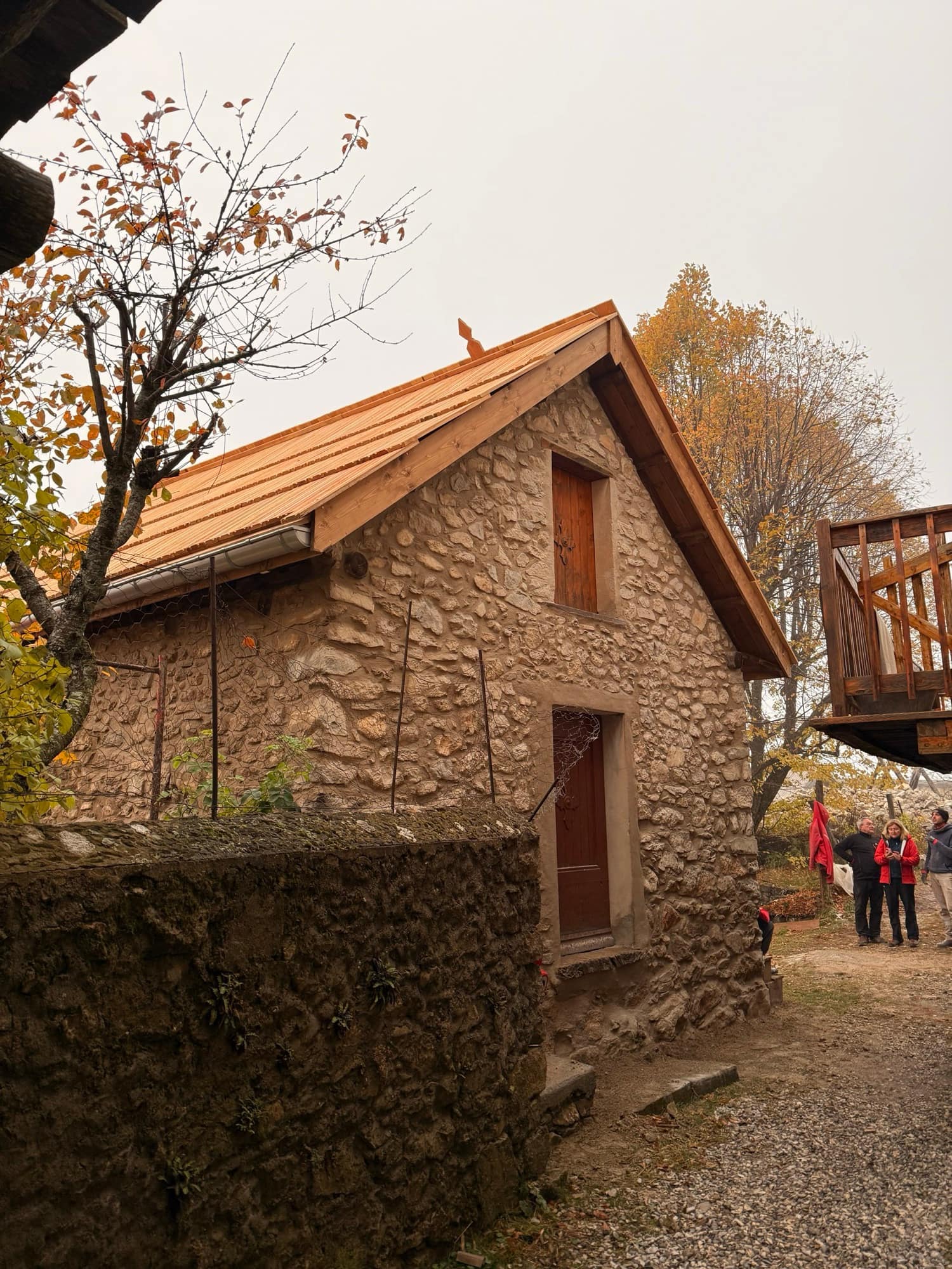 Bâtisse ancienne en pierre coiffée d'une charpente en bois neuve, à l'automne.
