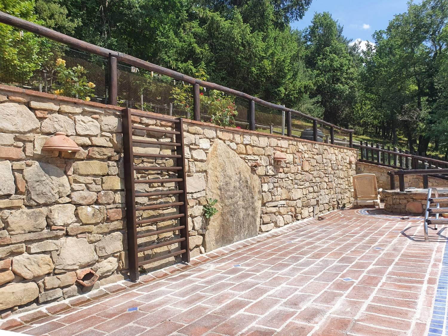 Terrasse en terre cuite bordée d'un mur en pierre, garde-corps de bois.